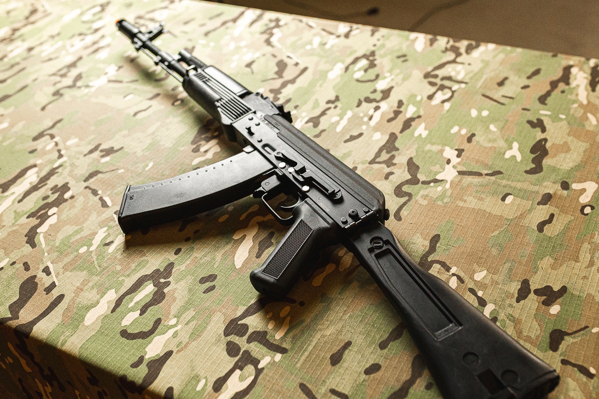 Rifle Airsoft AK 74MN Full Metal Preta Sobre a mesa camuflada